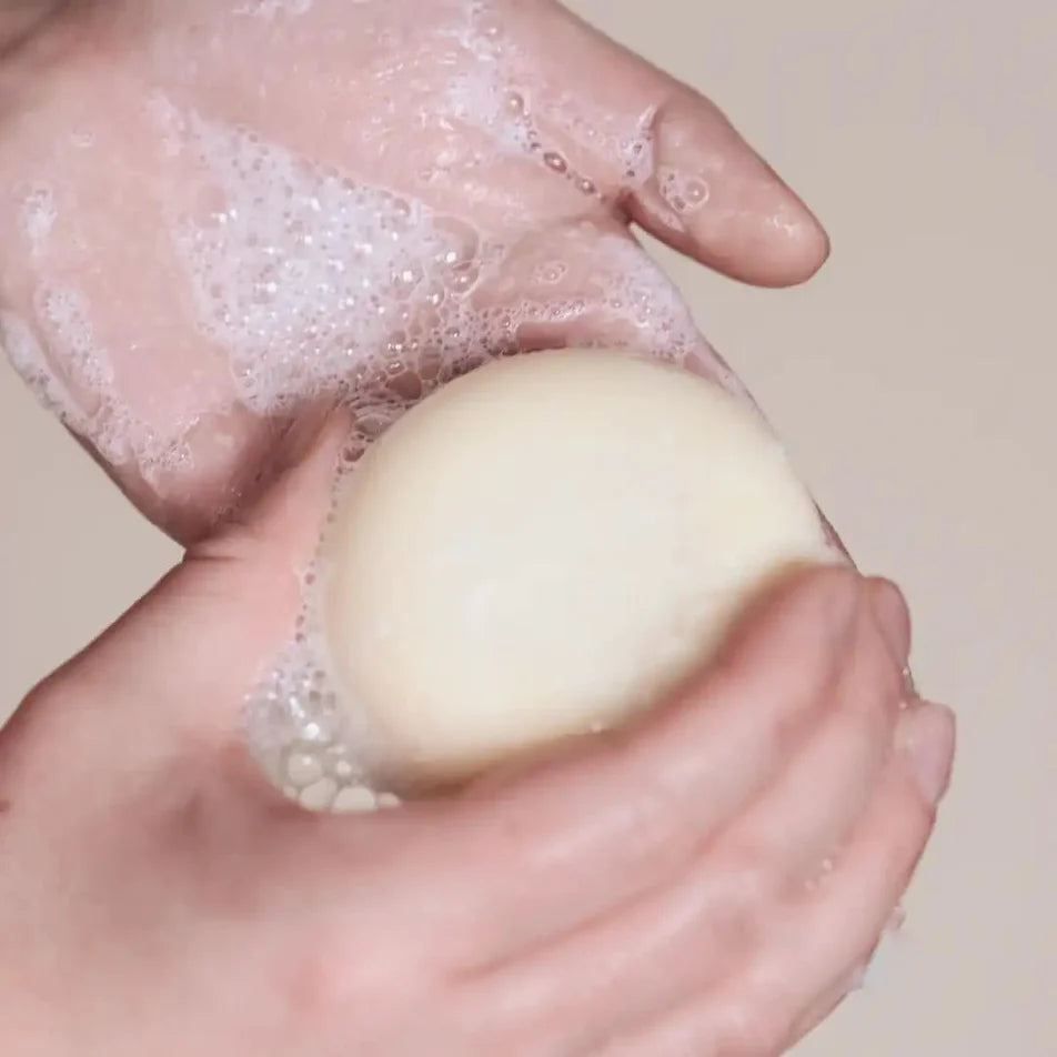 Un shampoing solide pour cheveux bouclés de la marque Endro dans des mains