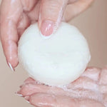 Un shampoing solide dans les mains d'une femme