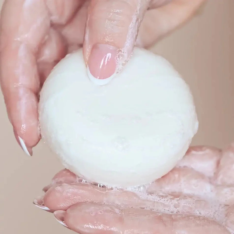 Un shampoing solide dans les mains d'une femme