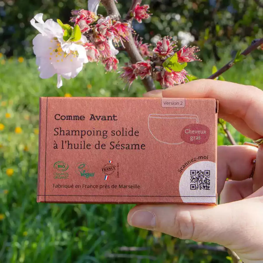 Une main tenant un shampoing solide à l'huile de sésame pour cheveux gras de la marque comme avant en 70g 