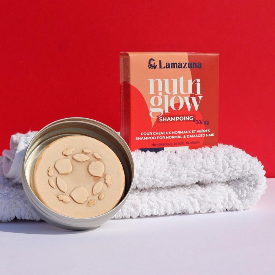 Shampoing solide Nutri Glow avec son emballage posé sur une serviette