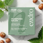 Shampoing solide Endro Ortie Huile Noisette pour cheveux gras avec emballage vert sur marbre blanc