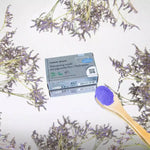 Un shampoing solide au pigment bleu ultramarine pour cheveux blonds et blancs de la marque comme avant avec une cuillère en bois et de la poudre bleue