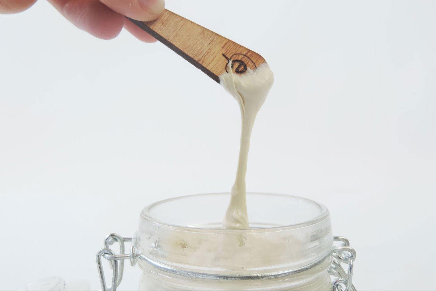 Zoom sur une Une Petite spatule en bois de 6 cm de la marque Endro en train d'être utilisé pour prélevé un lait corps hydratant