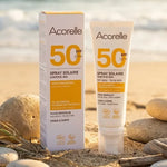 Spray solaire bio Acorelle SPF 50 100ml sur plage avec galets et herbes marines