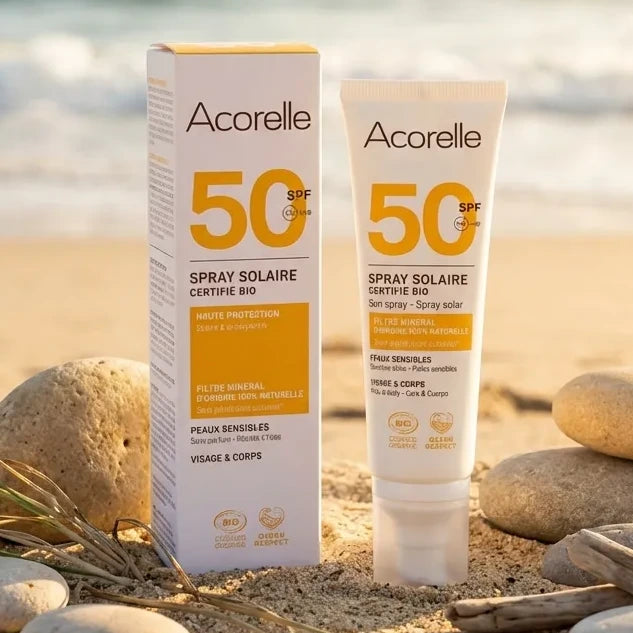 Spray solaire bio Acorelle SPF 50 100ml sur plage avec galets et herbes marines