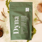 Un super matcha de la marque Dyna avec les ingrédients bruts disposés autour