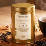 Thé noir Lapsang Souchong bio 100g en boîte dorée avec tasse fumante sur surface bois