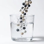 Trois billes de céramique filtrantes japonaises versées dans un verre d'eau pour purification