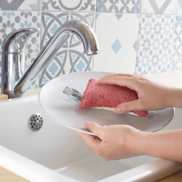 Une éponge Lavable Corail Écologique Anotherway utilisée pour laver une assiette