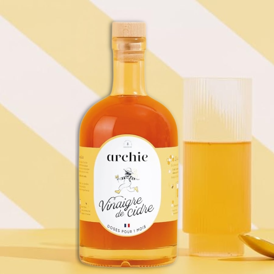 Une bouteille de 500ml de Vinaigre de cidre au miel bio Archie côté d'un verre rempli