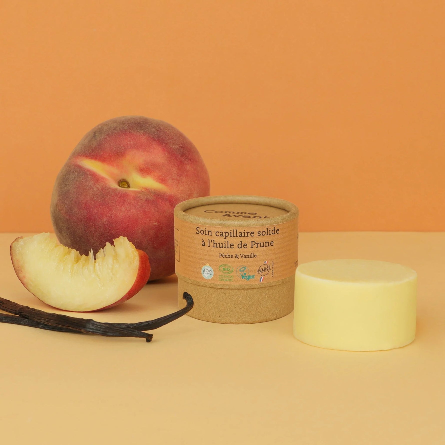 Visuel d'ambiance d'ne boite kraft de 50 grammes de Soin Capillaire Solide à l'huile de Prune Pêche & Vanille Bio Comme avant